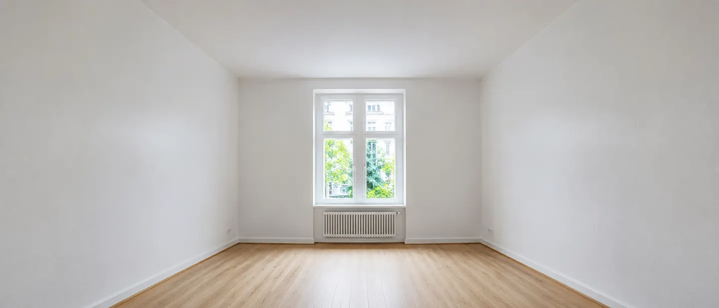 Heller Wohnraum nach dem Streichen: weiße Wände, saubere Kante zur Decke, Tageslicht vom Fenster
